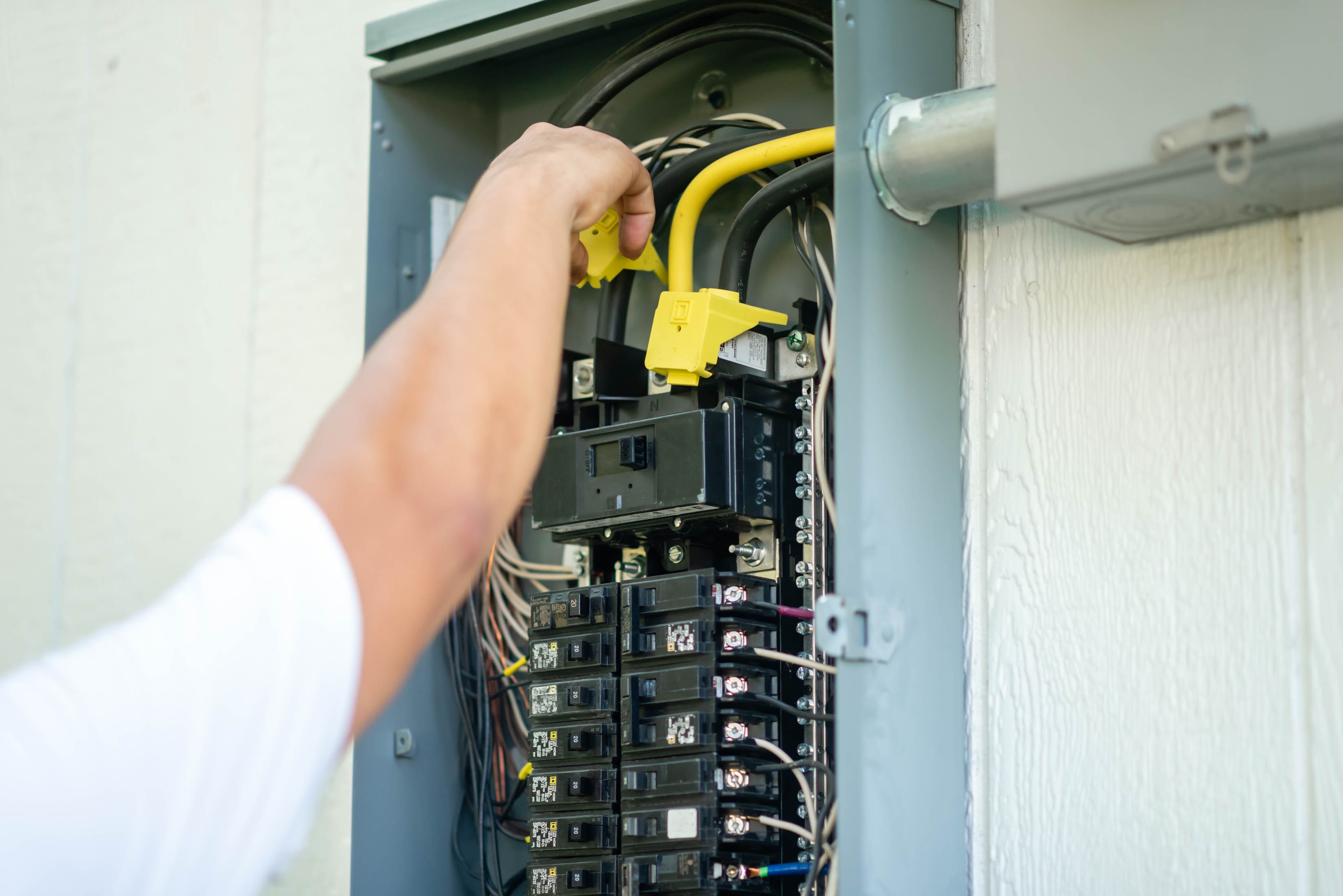 Hand routing yellow Romex wire through residential main panel — Casta Energy panel service