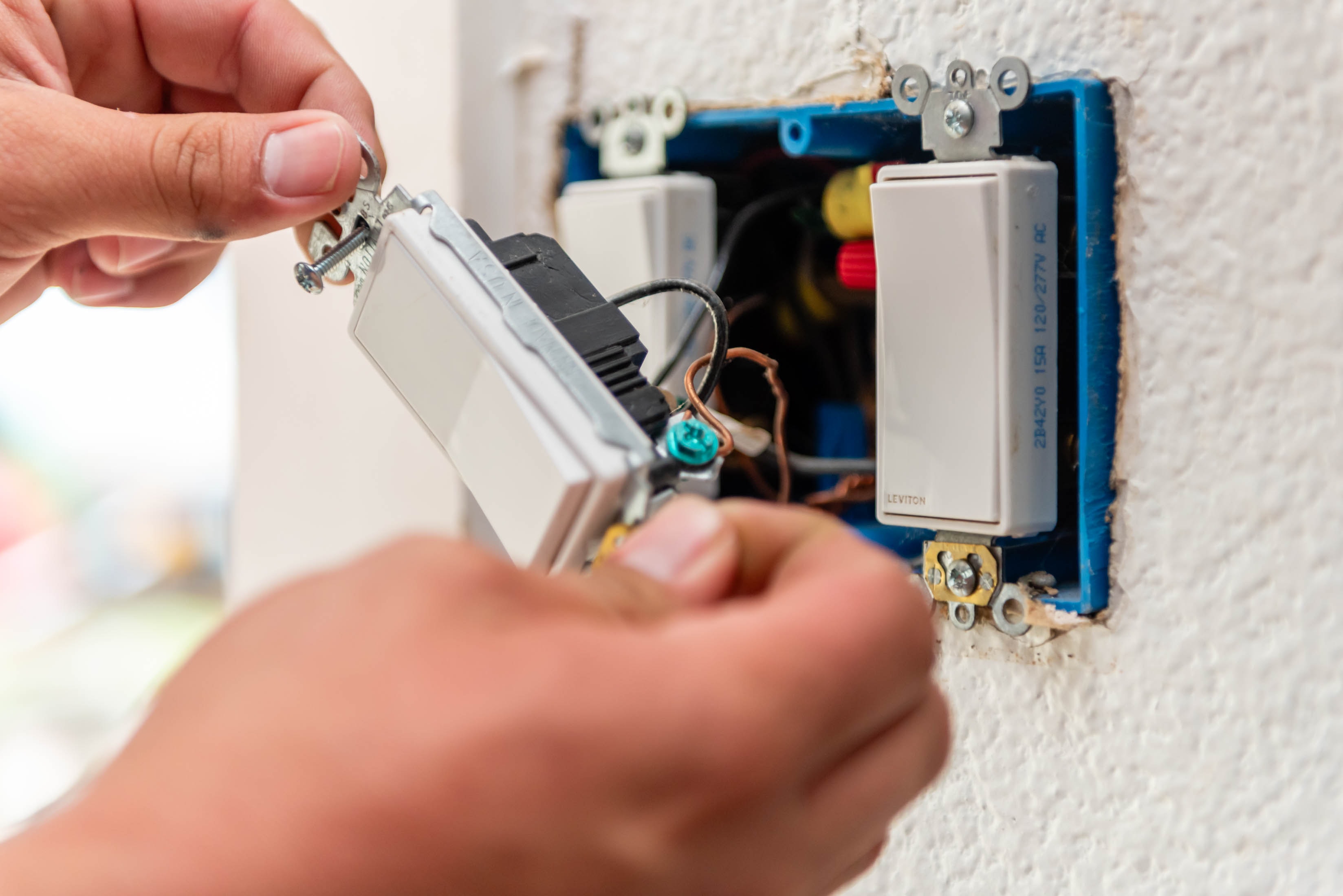 Hands wiring Leviton smart switch into blue gang box — Casta Energy residential electrical