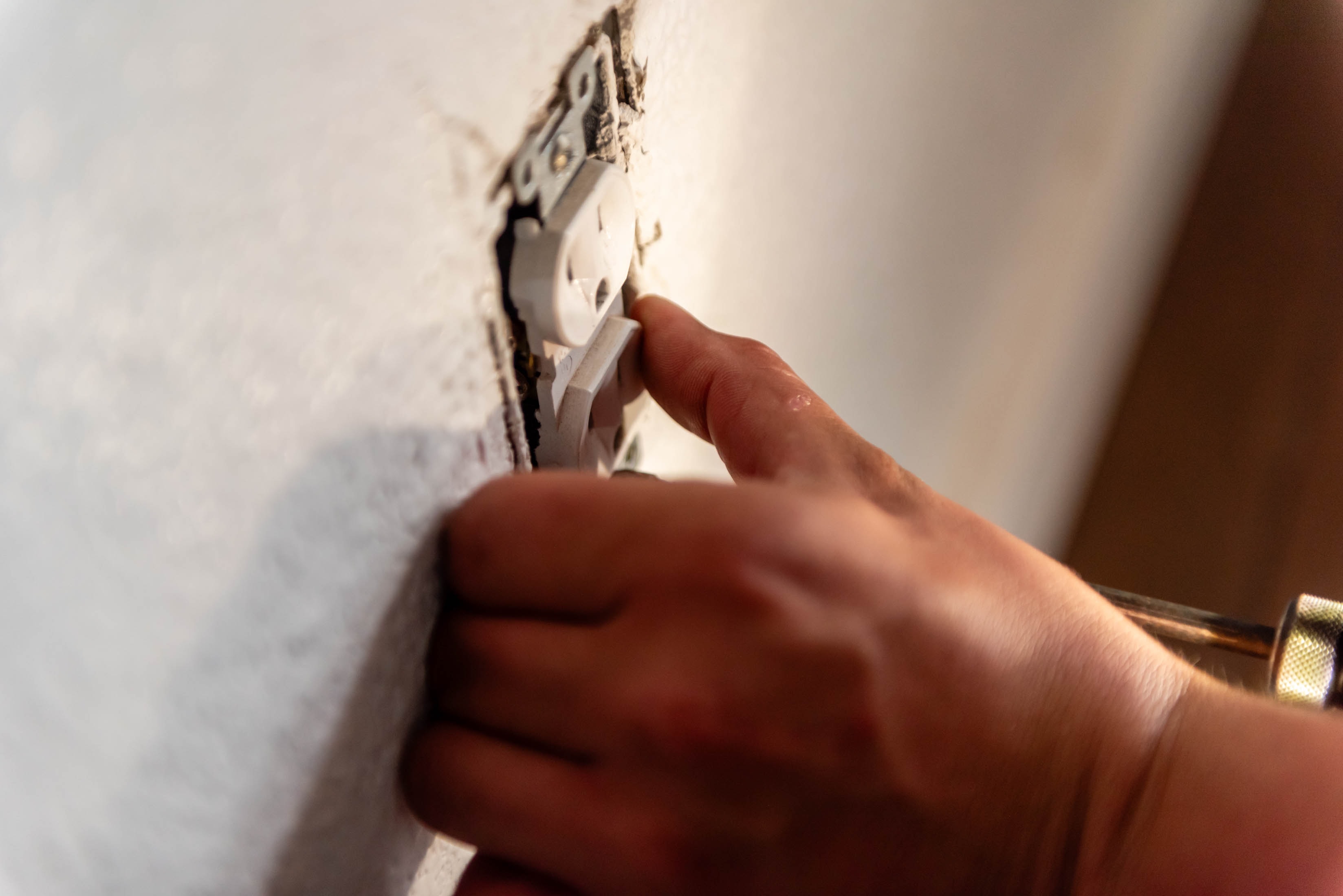 Hand pressing duplex outlet into wall box — Casta Energy residential outlet installation detail