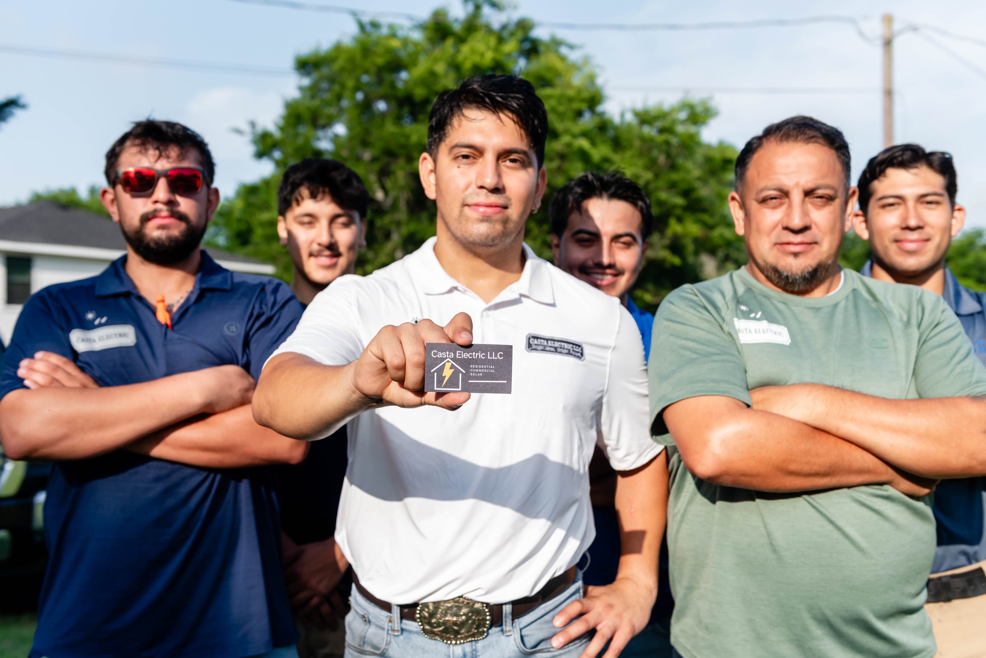 Casta Electric LLC team with owner holding business card — family-owned DFW electrician