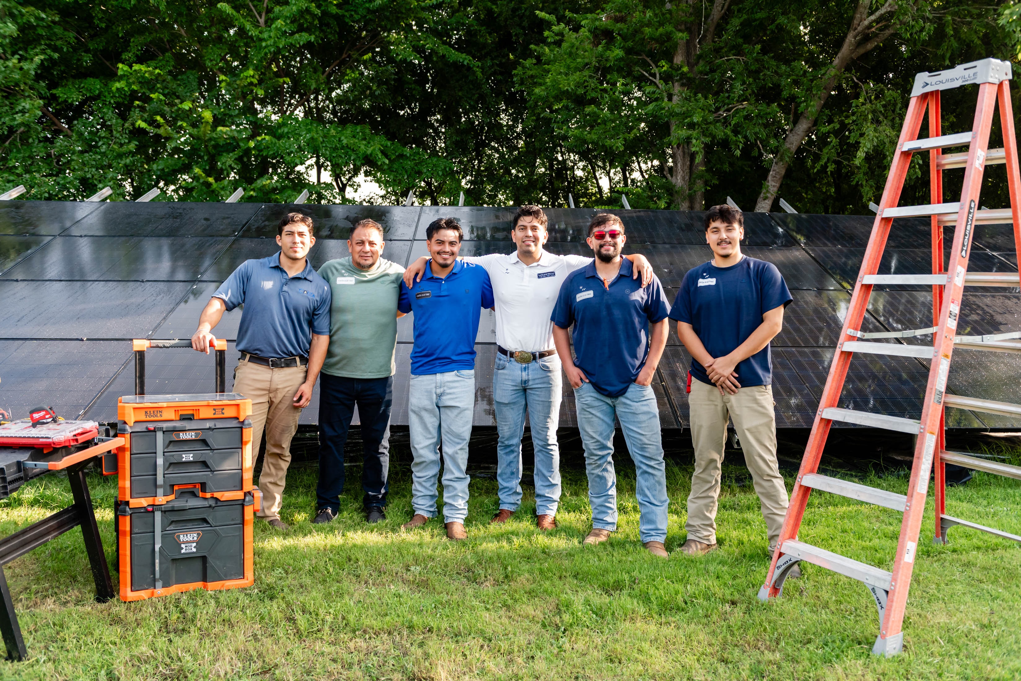 Casta Energy team smiling together in front of solar panel array