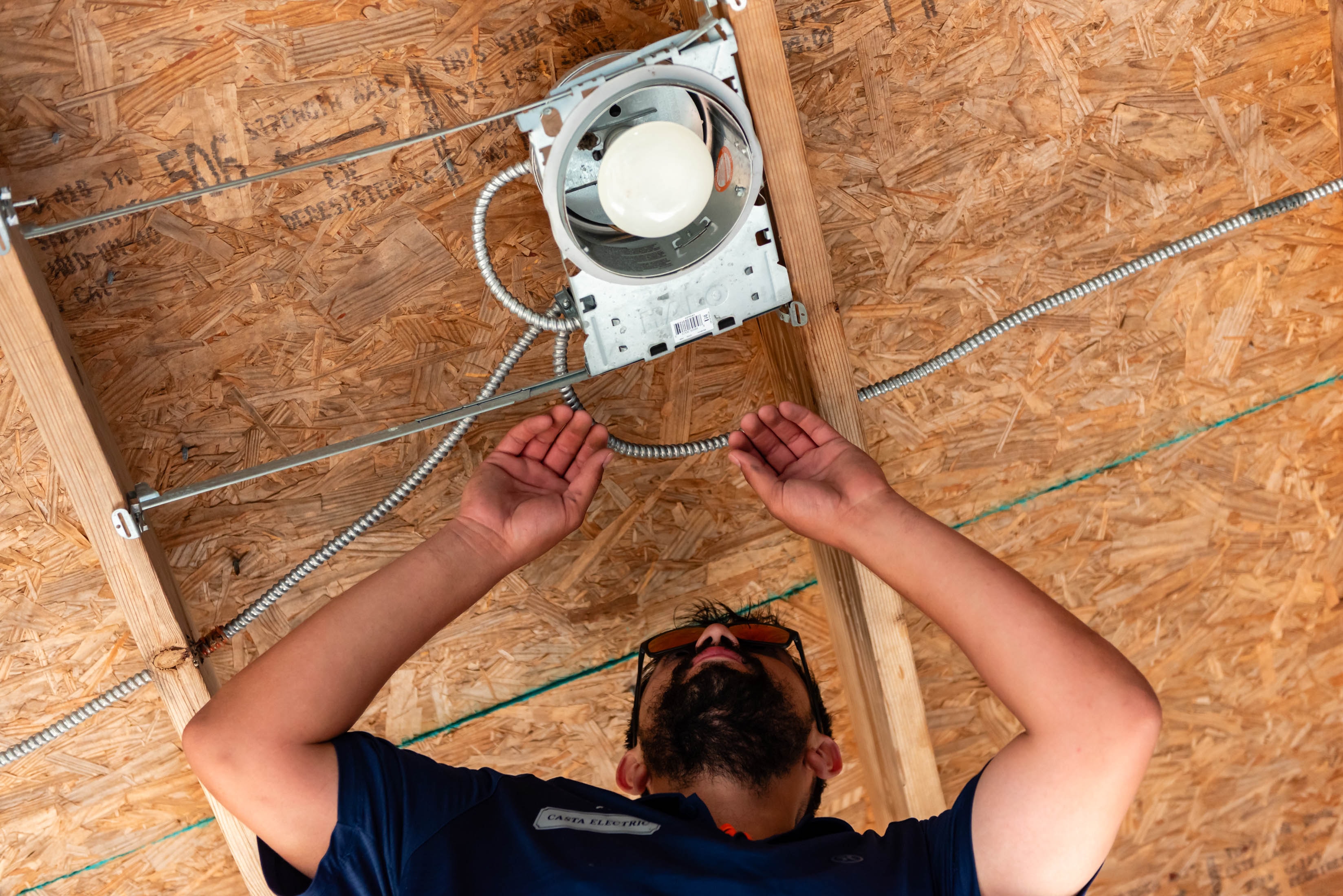 Overhead view of Casta Electric tech routing armored cable to ceiling fixture