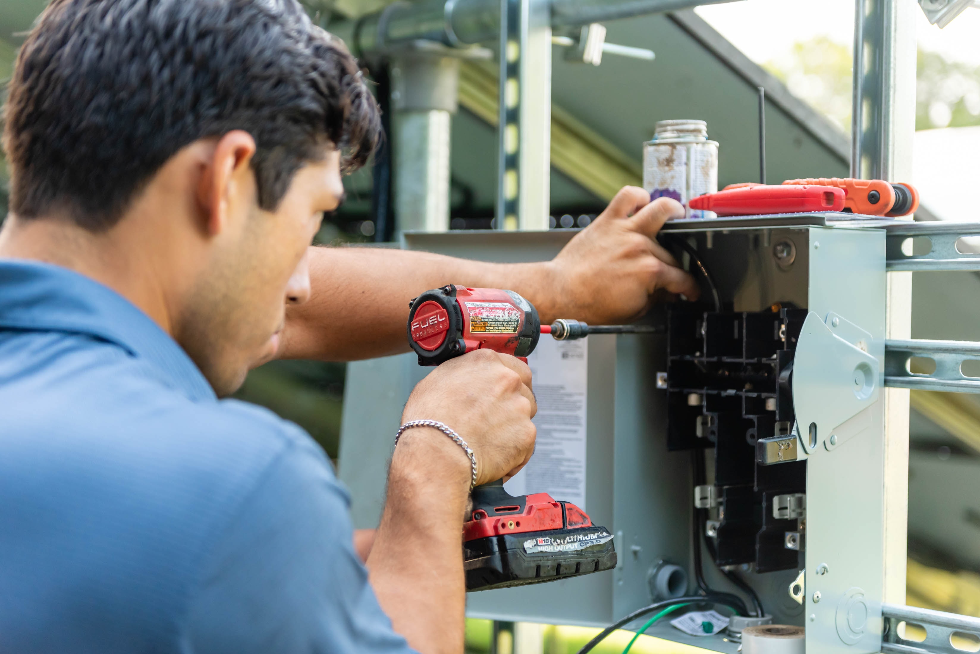Casta Energy technician drilling into disconnect box with Milwaukee drill