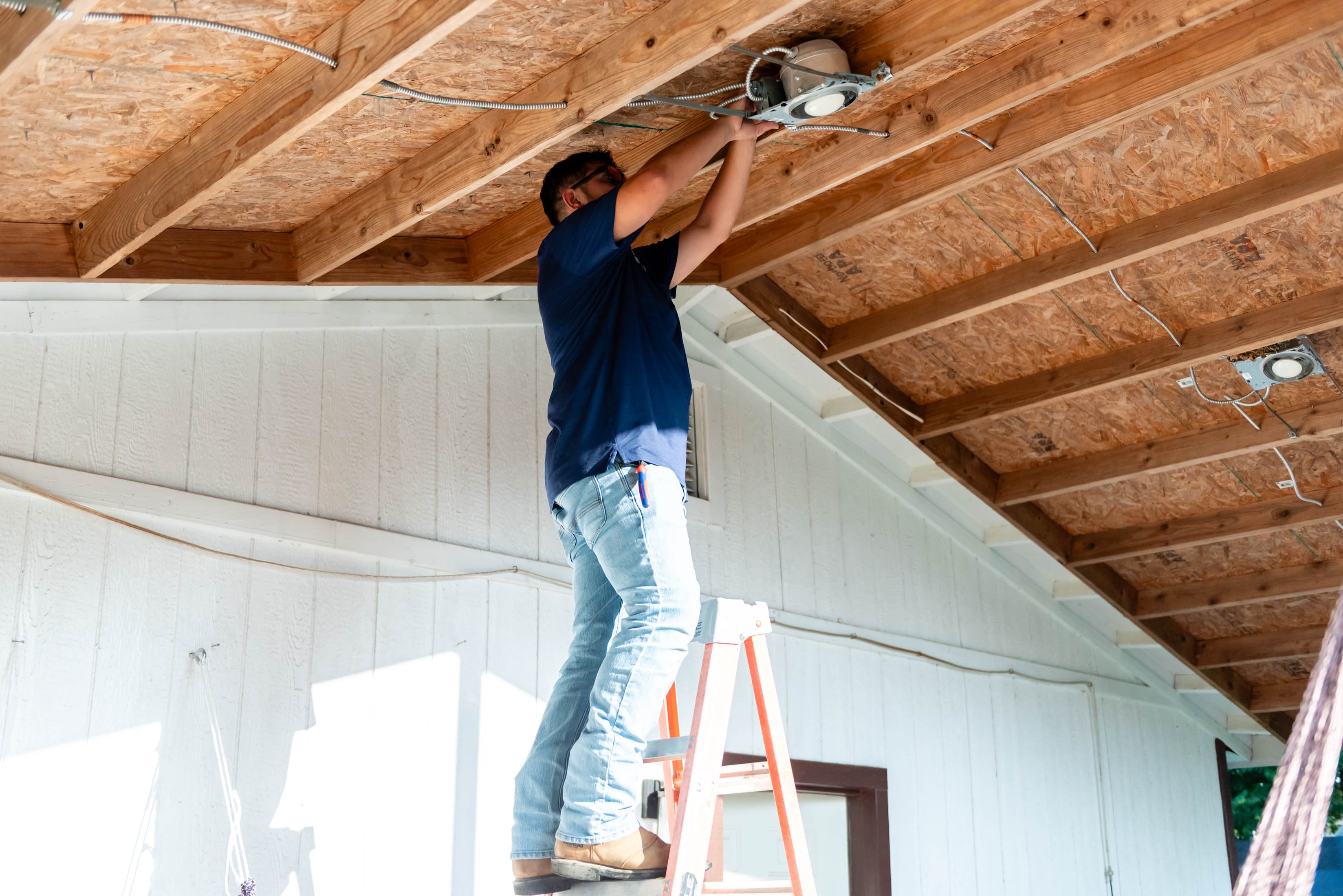 Casta Energy technician on ladder securing ceiling fixture from the side