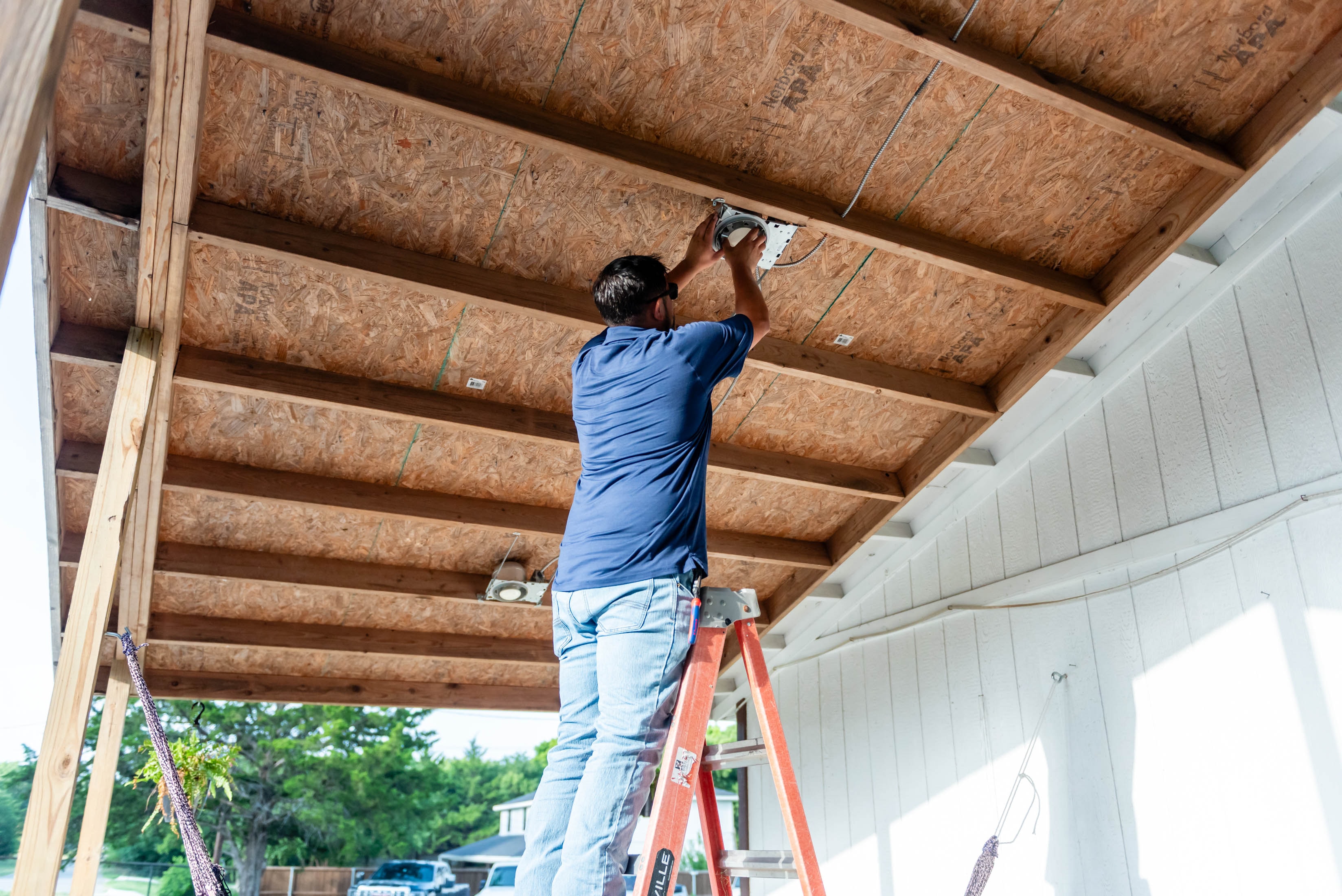 Casta Energy electrician on ladder installing recessed lights in OSB ceiling