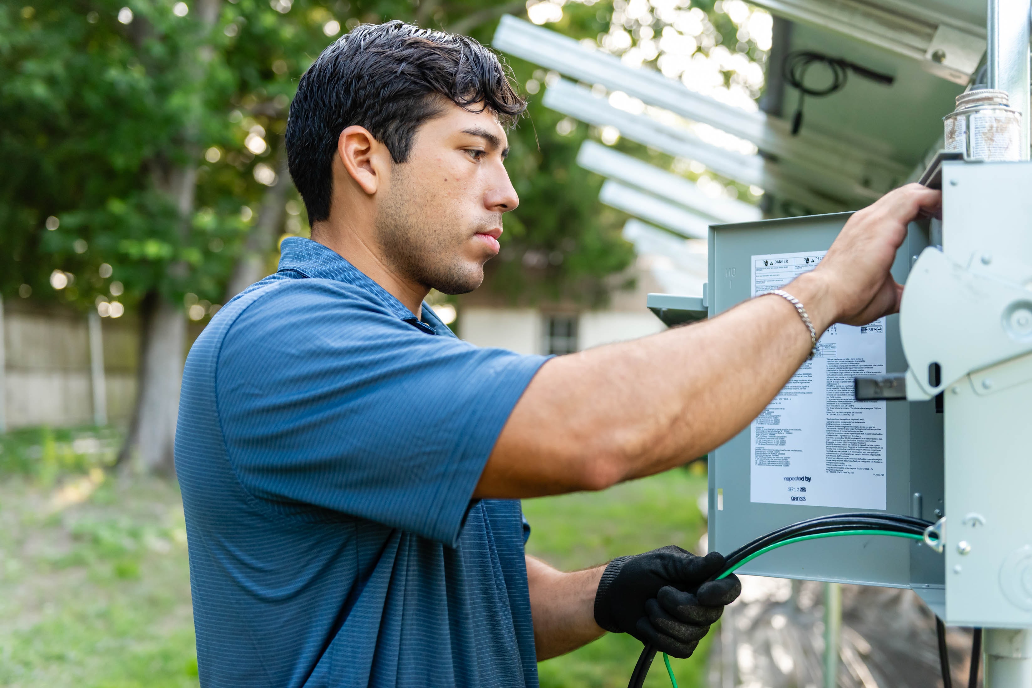 Casta Energy technician wiring an outdoor electrical panel under solar array