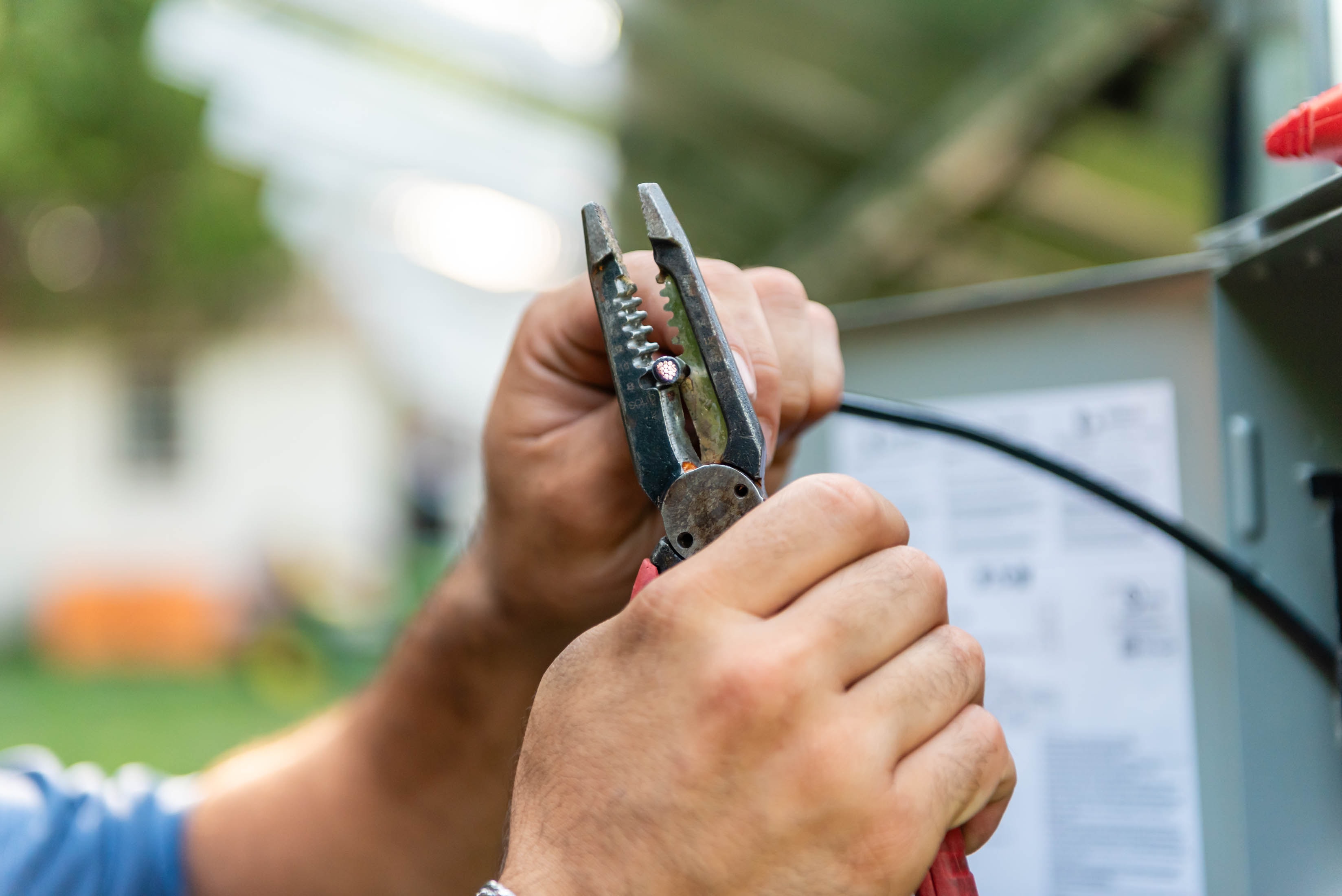 Casta Energy technician using pliers to pull wire at electrical panel