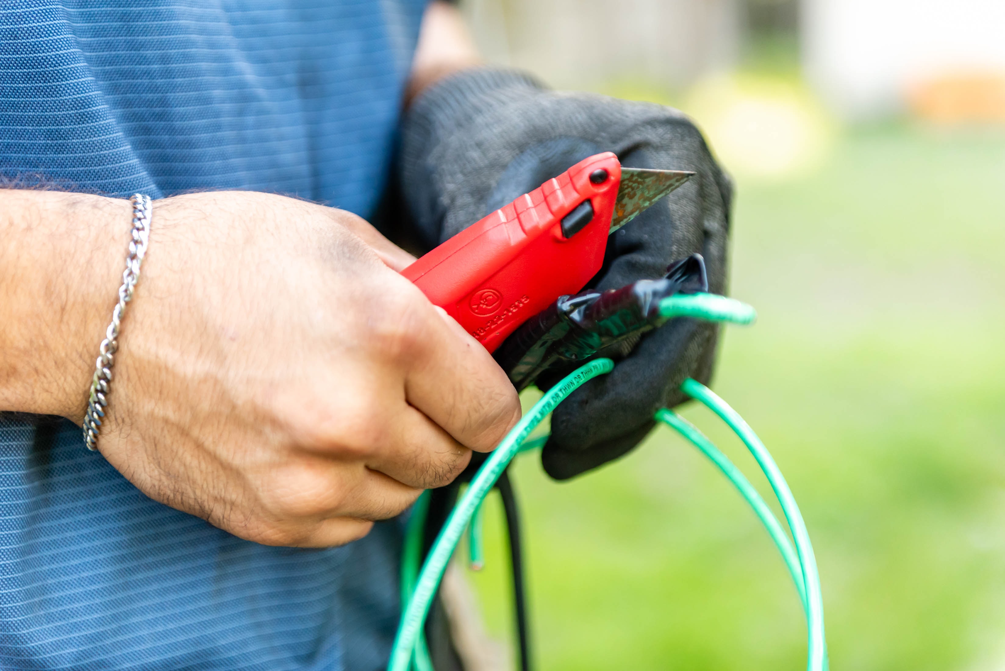Casta Energy tech cutting green ground wire with utility knife — detail shot